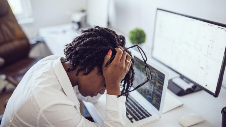 Demotivated employee sitting at a computer and feeling disengaged at work